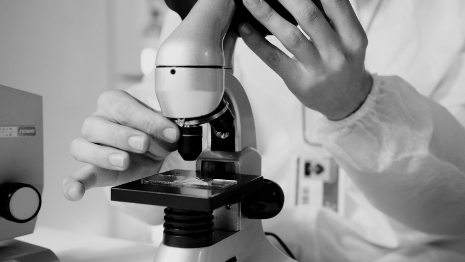 Chercheur observant un échantillon au microscope en laboratoire