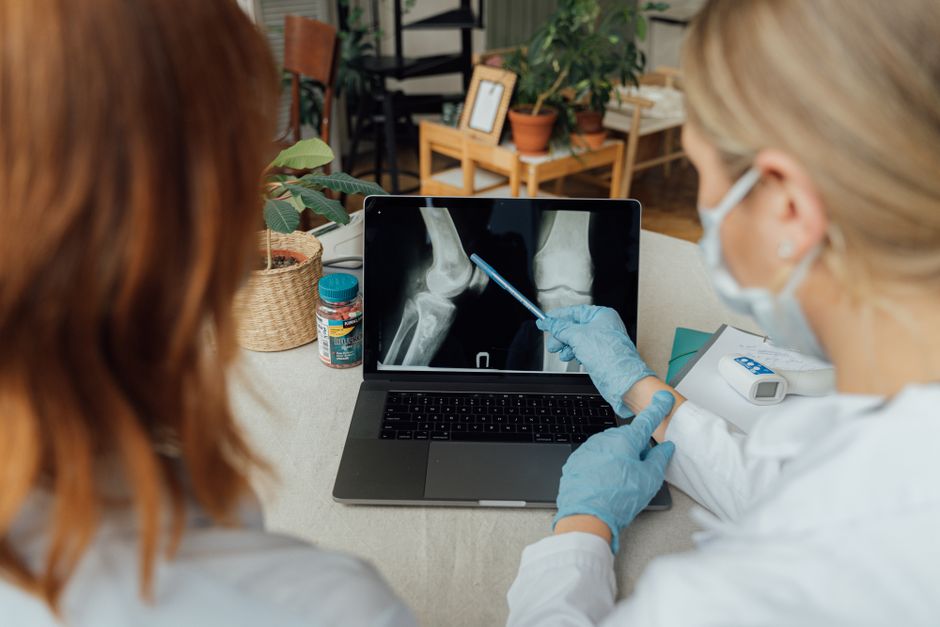 Deux professionnels de santé examinent des radiographies sur un ordinateur.
