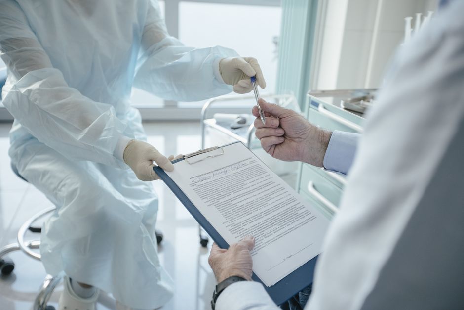 Un médecin remet un document à un patient pour signature