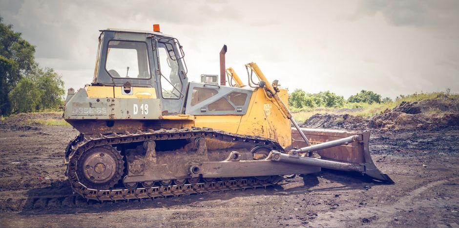 Un bulldozer sur un chantier boueux sous un ciel nuageux