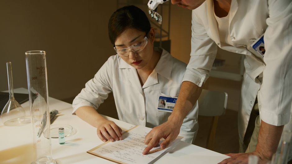 Des chercheurs en blouse blanche examinent des notes scientifiques en laboratoire
