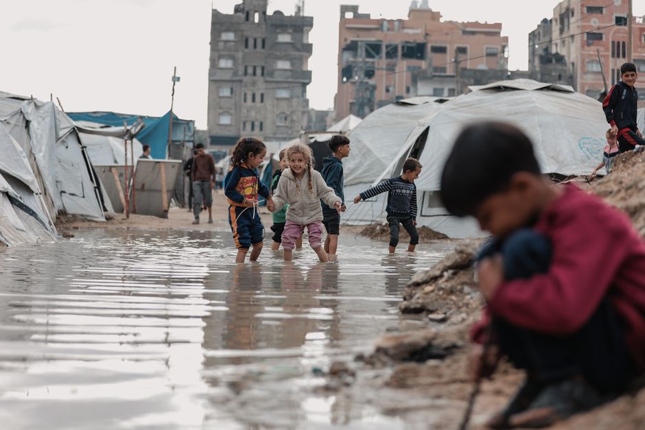 Des enfants jouent dans l'eau près de tentes de réfugiés à Gaza