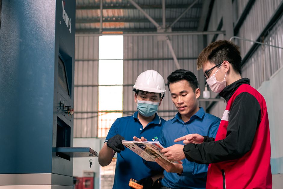 Des ouvriers en entrepôt examinent ensemble des plans de production.
