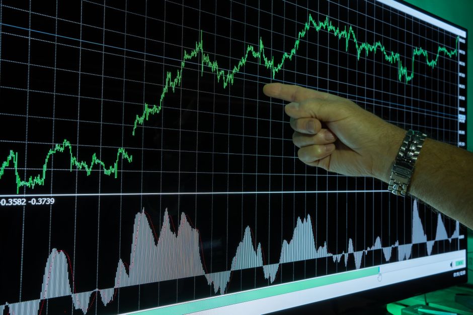 Main pointant des courbes d'analyse financière sur un graphique d'évolution de marché.
