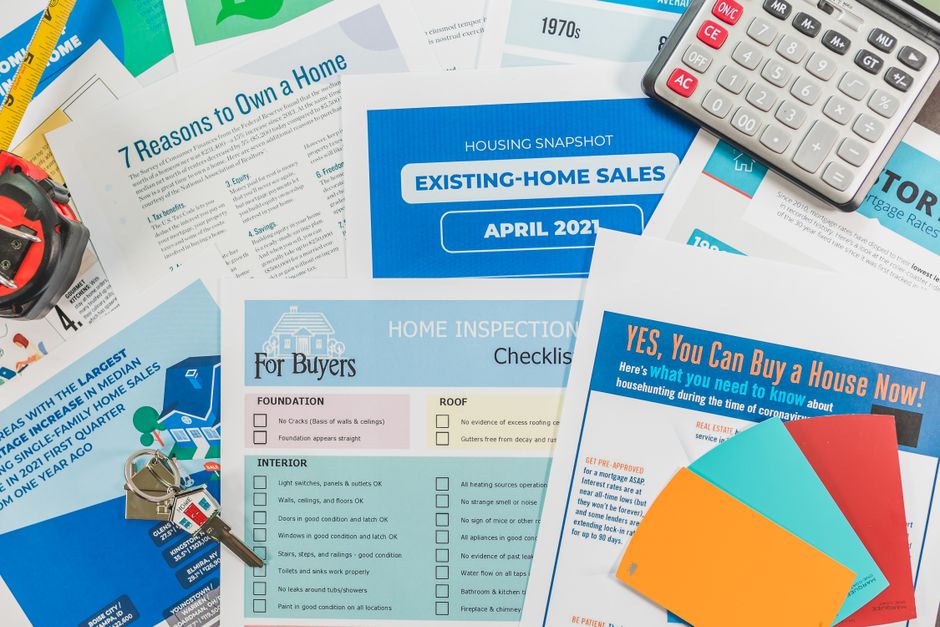 Des brochures immobilières, une checklist et une calculatrice posées à plat.