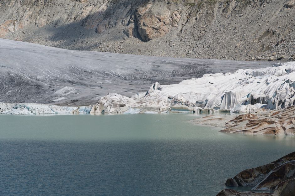 Glacier de montagne avec lac bleu et sommets enneigés alentour
