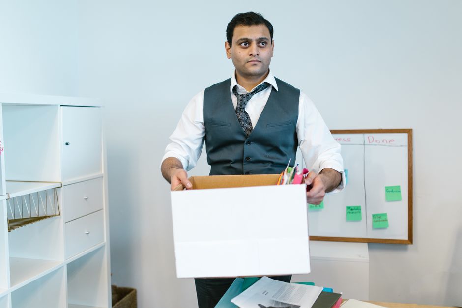 Un homme range ses affaires professionnelles dans un carton de déménagement
