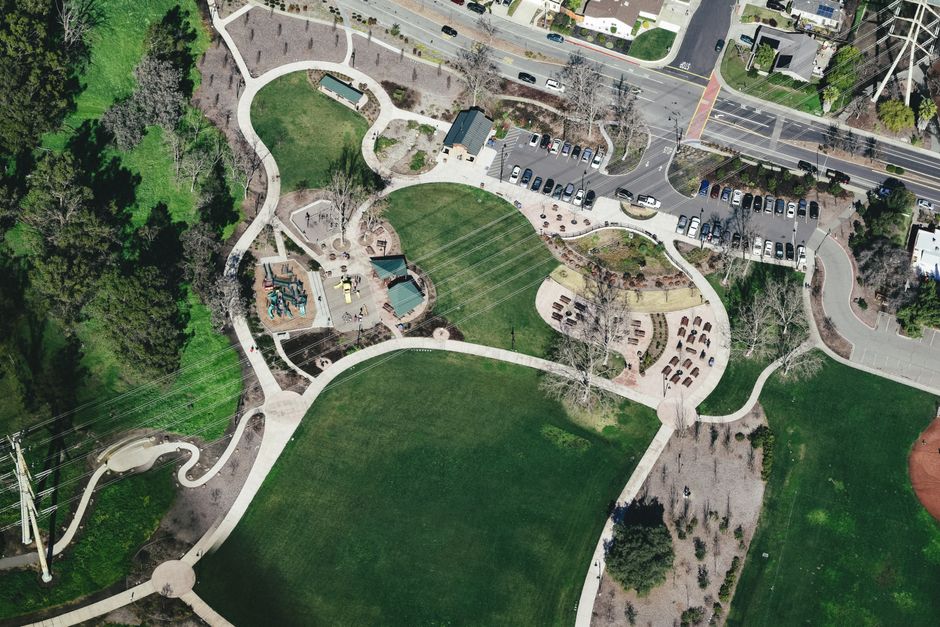 Vue aérienne d'un parc urbain avec routes sinueuses, végétation et voitures garées