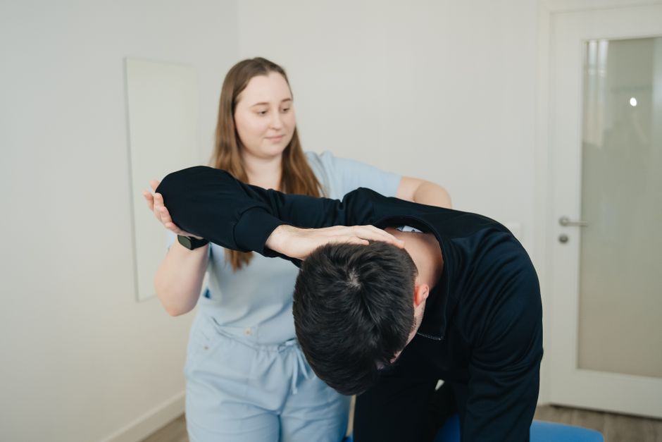 Un kinésithérapeute aide un patient dans un exercice d'étirement.