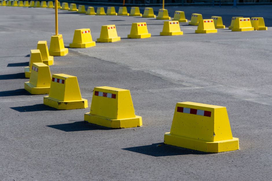 Des barrières de circulation jaunes alignées sur une route asphaltée.