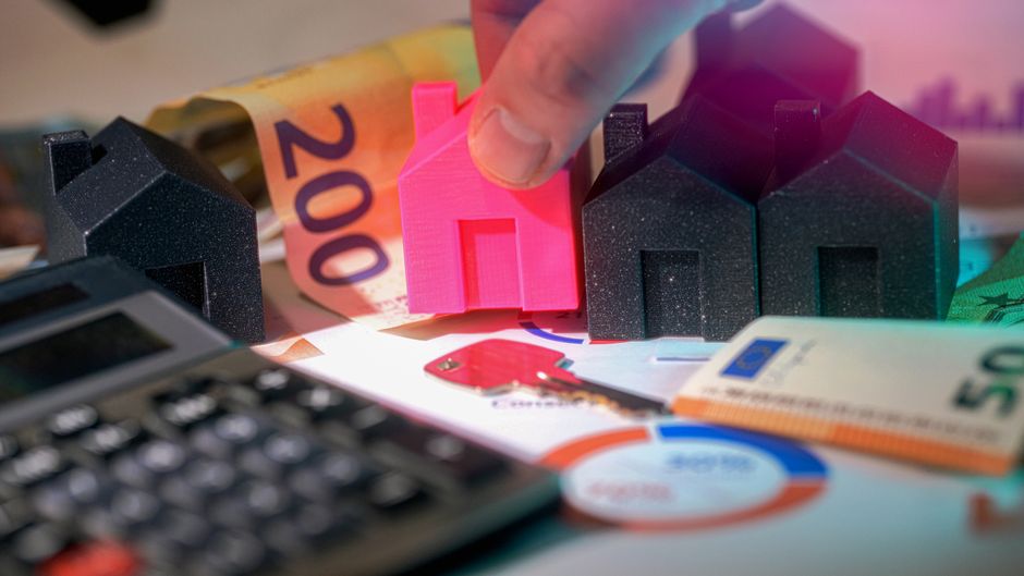 Petites maisons modèles, billets en euros et calculatrice sur une surface neutre