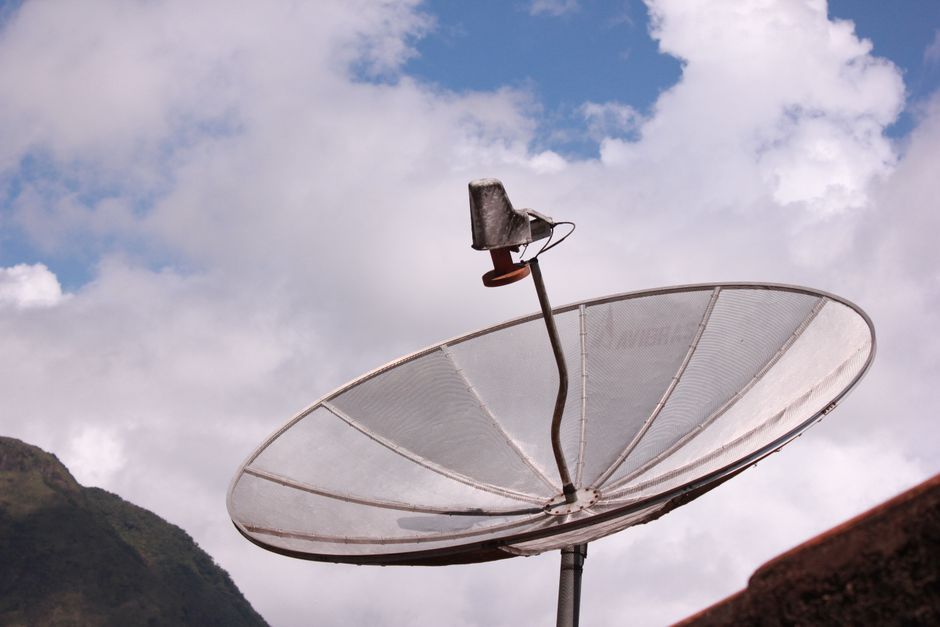 Antenne parabolique argentée pointée vers le ciel bleu
