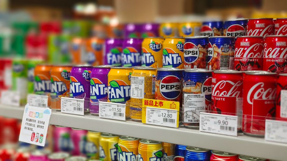 Canettes de sodas avec étiquettes de prix sur des rayons de supermarché