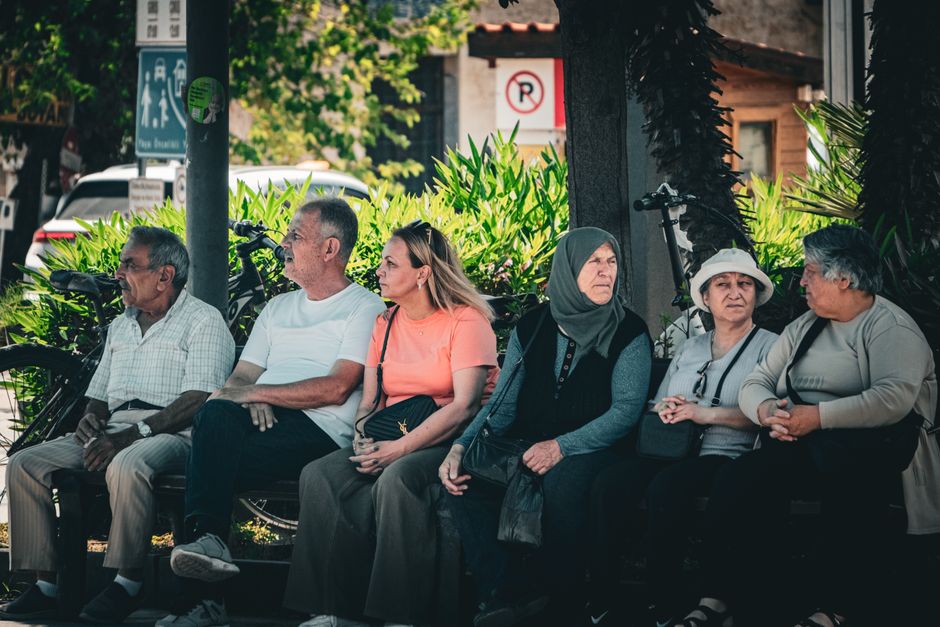 Un groupe de personnes assis ensemble sur un banc discutent.