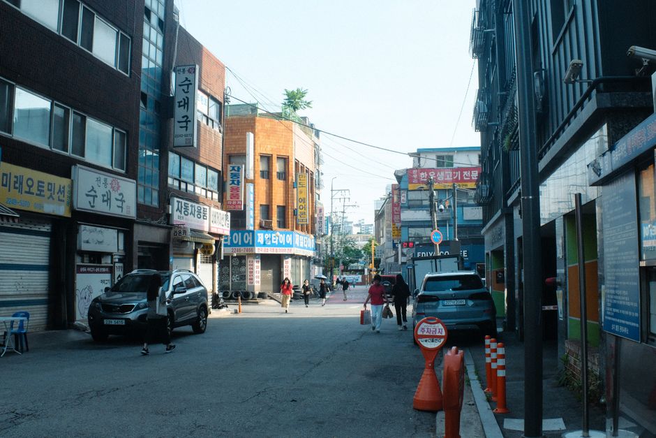 Une rue animée de Séoul avec piétons, voitures et immeubles urbains.