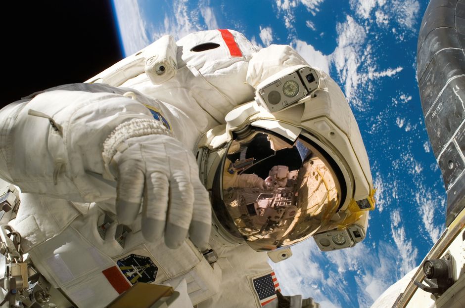 Astronaute en sortie extravéhiculaire avec la Terre visible en arrière-plan