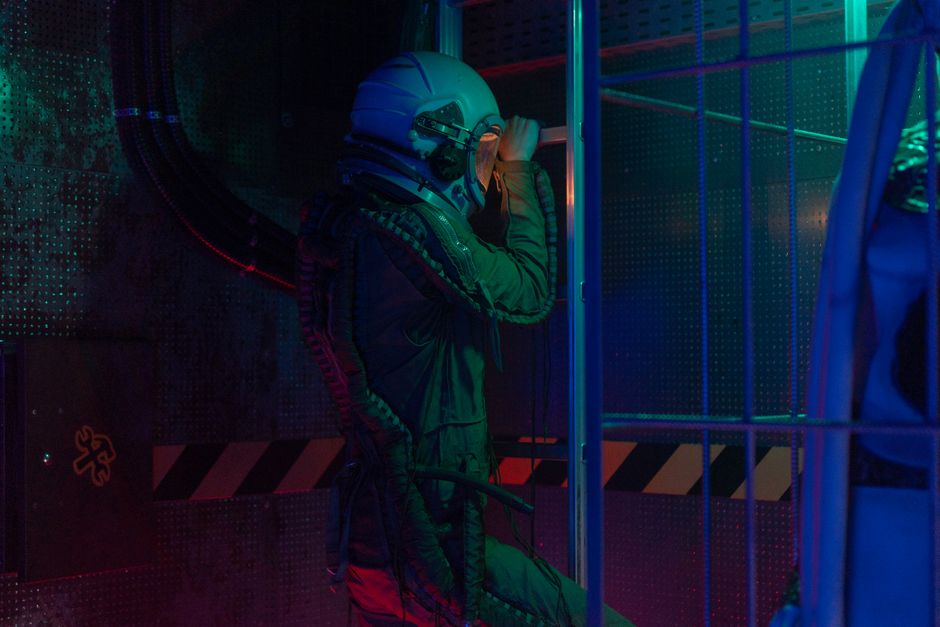 Un astronaute en combinaison spatiale explore un environnement intérieur éclairé.