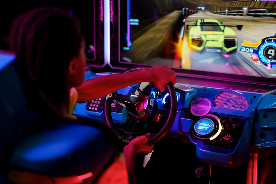 Personne jouant à un jeu de course en arcade avec commandes immersives.