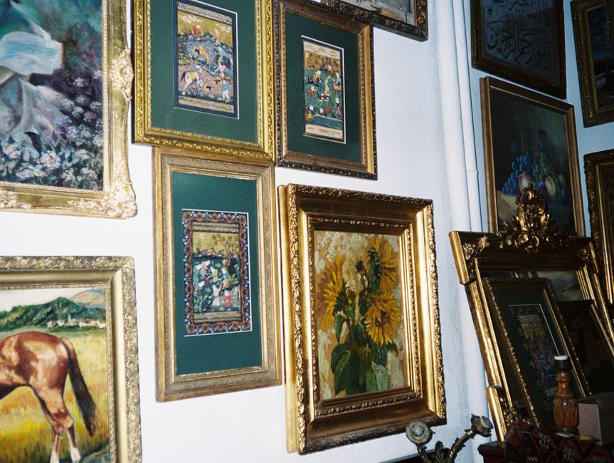 Cadres dorés ornementaux exposant des peintures dans une galerie.