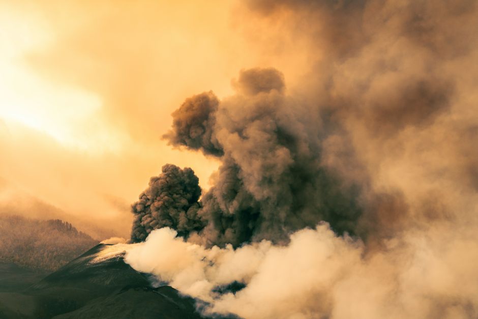 Nuage massif de cendres volcaniques s'élevant dans l'atmosphère au coucher de soleil