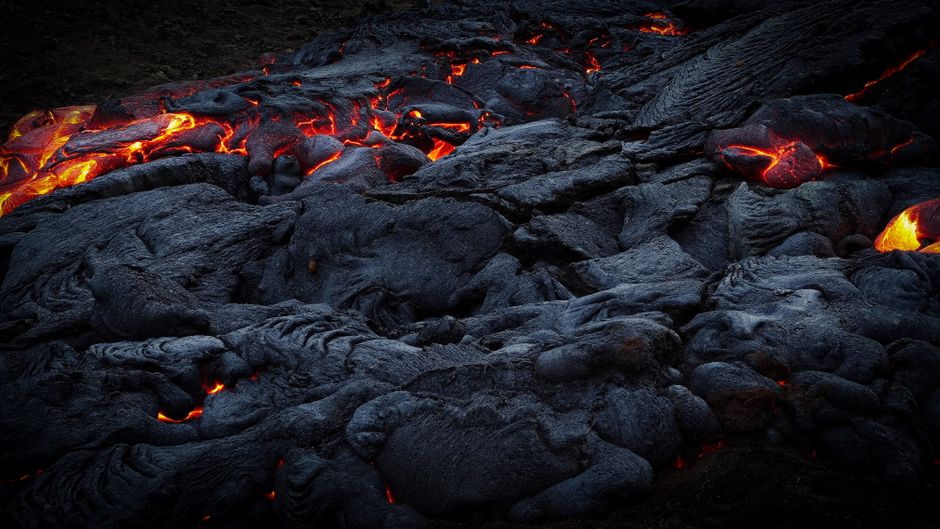 Lave incandescente s'écoulant sur une roche volcanique sombre