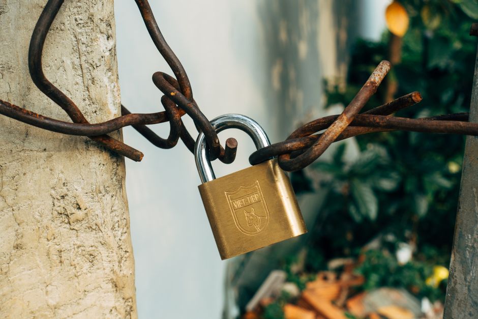 Un cadenas en laiton fermant une chaîne sur un poteau de béton