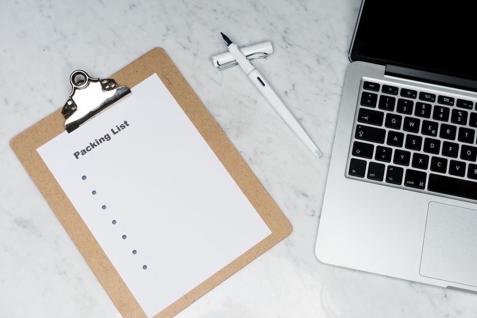 Bloc-notes avec liste de préparation, stylo et ordinateur portable sur un bureau