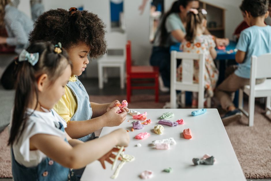 Enfants à une table de maternelle jouant avec de la pâte à modeler colorée