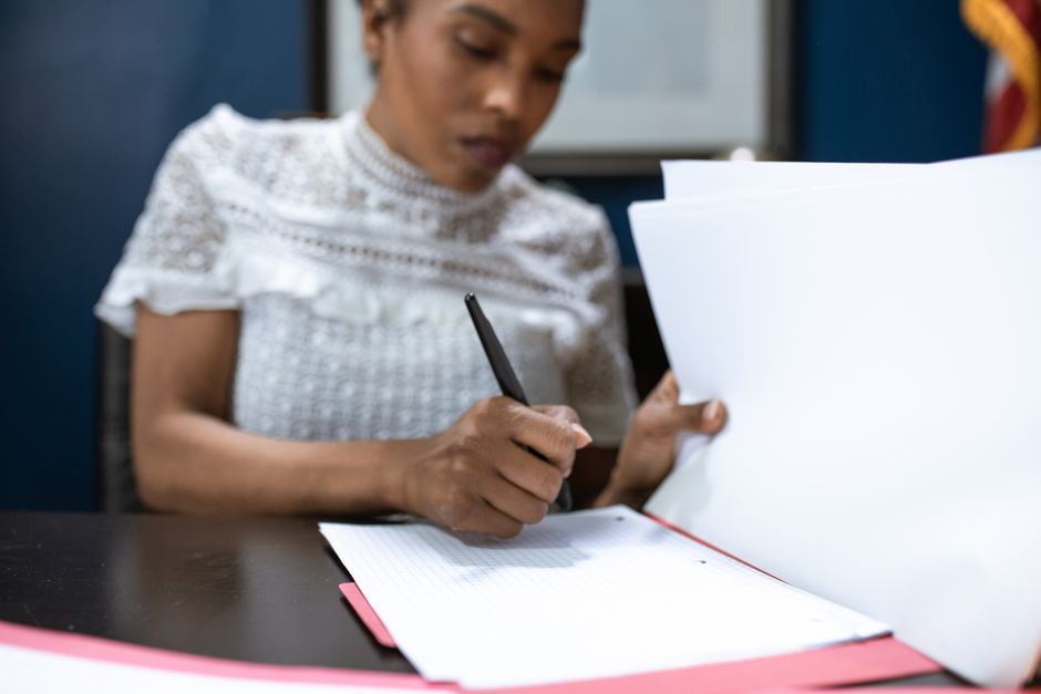 Une femme signe des documents administratifs dans un bureau