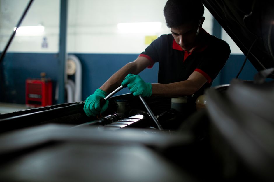 Mécanicien en atelier vérifiant un moteur automobile avec une clé dynamométrique.