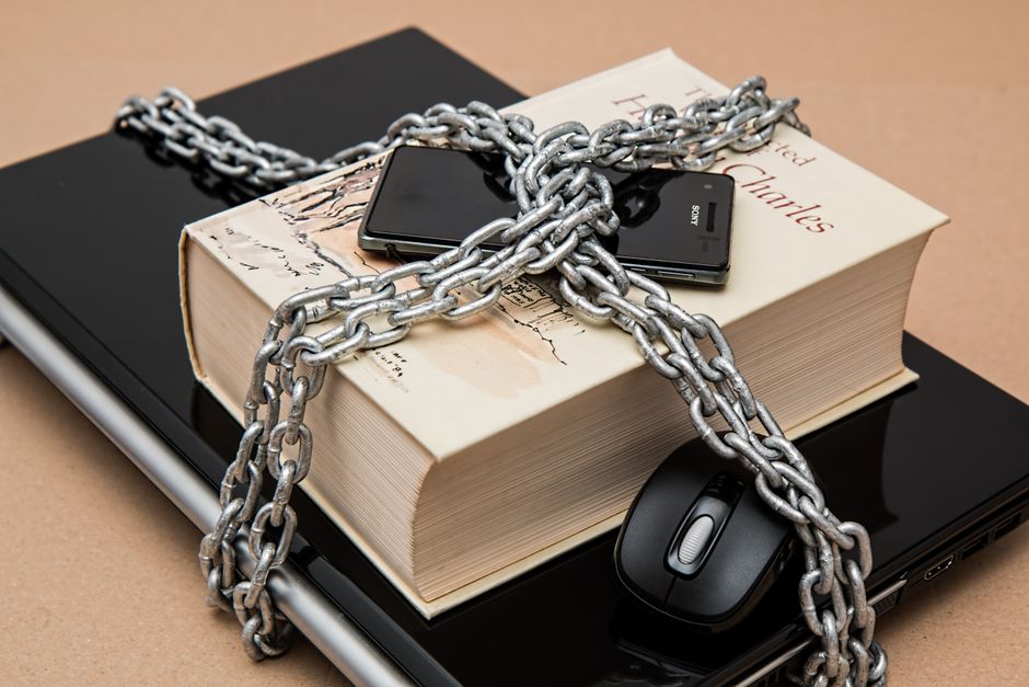 Téléphone, ordinateur portable et livre attachés par une chaîne de sécurité