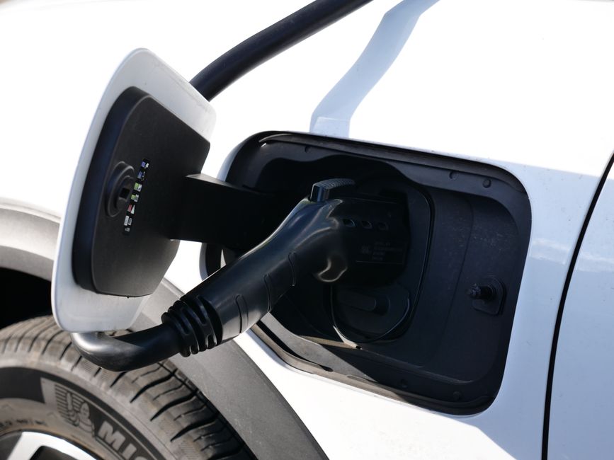 Gros plan sur un connecteur de recharge branché au port d'une voiture électrique