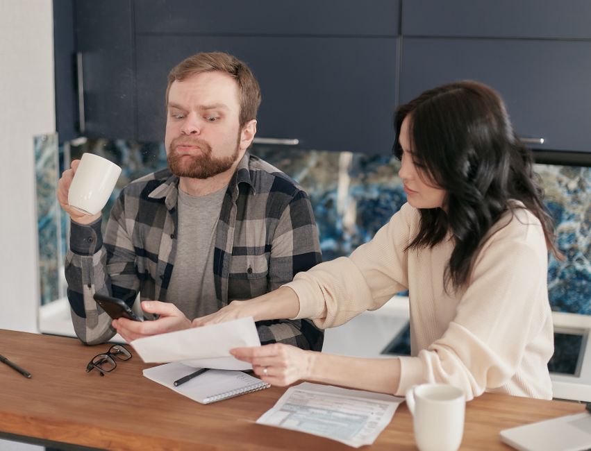 Un couple consulte ses factures à la table de la cuisine.