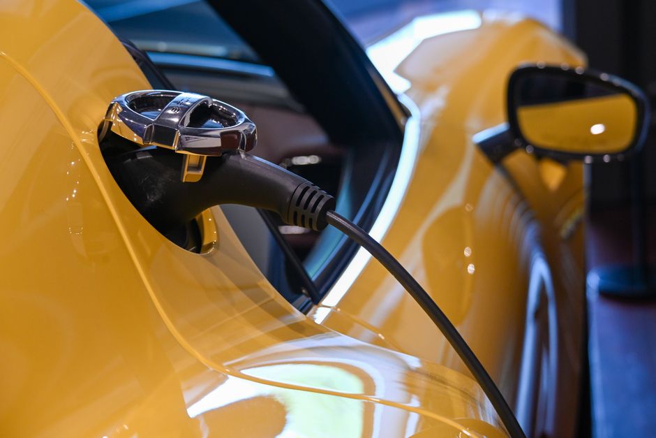 Câble de recharge branché sur un véhicule électrique jaune en intérieur