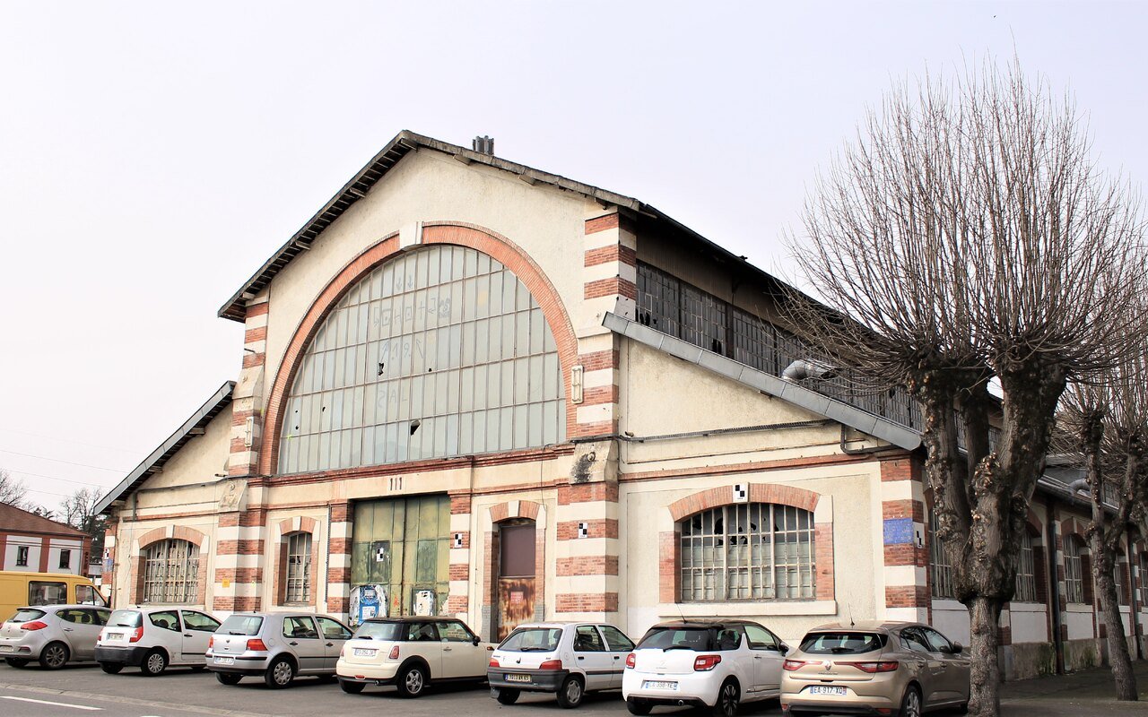 La façade en brique et pierre d'un grand atelier de l'arsenal de Tarbes, surmontée d'une verrière cintrée