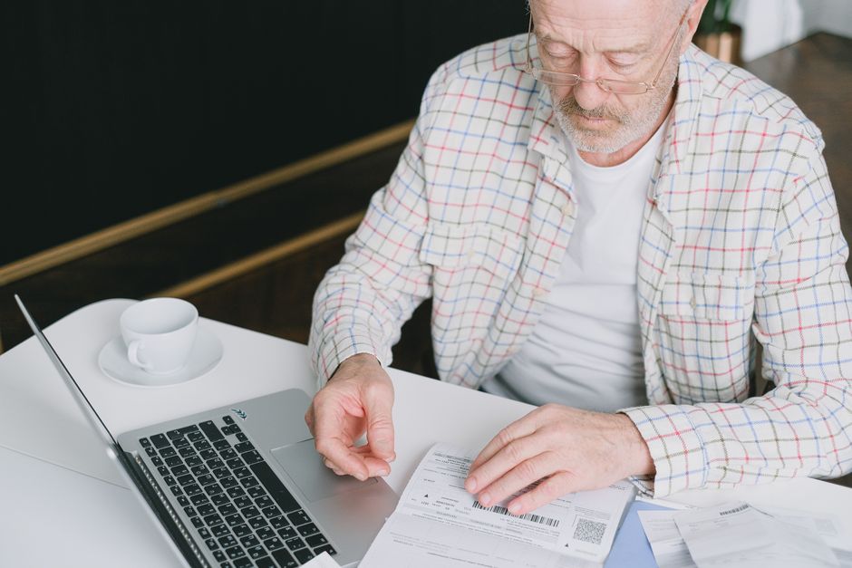 Un homme âgé consulte des documents à son ordinateur