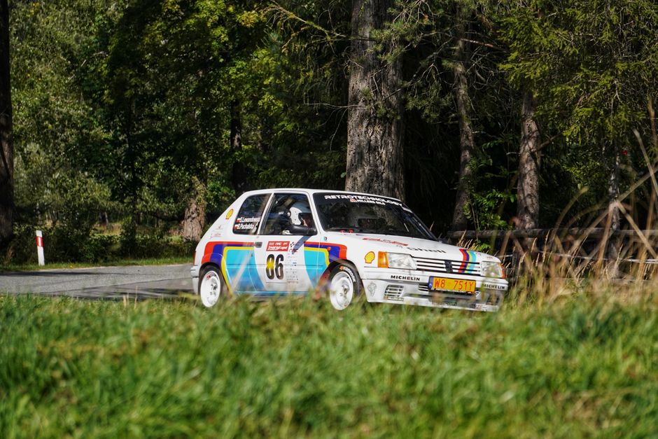 Une voiture de rallye rétro circulant sur un chemin forestier.