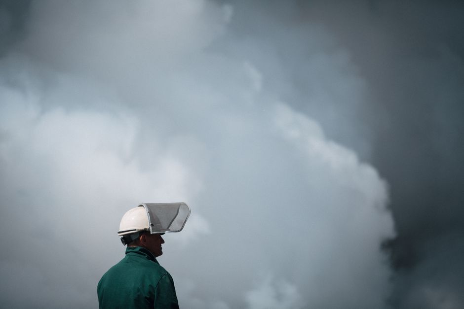 Un ouvrier en équipement de protection face à une pollution atmosphérique industrielle.