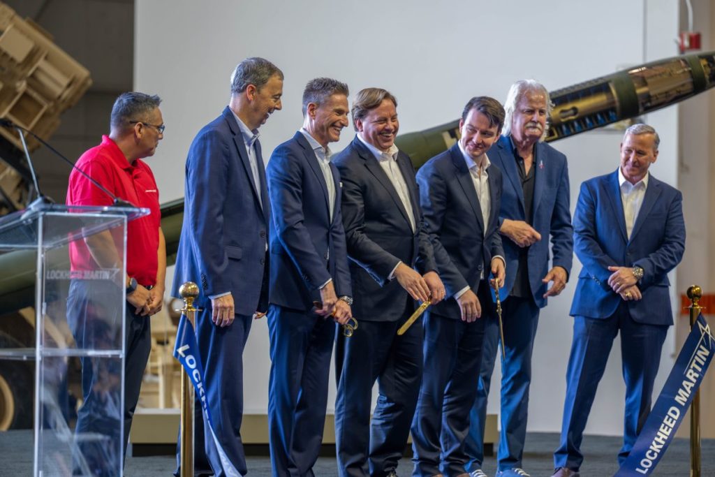 Groupe de sept responsables en costume tenant des pelles dorées lors d'une cérémonie industrielle