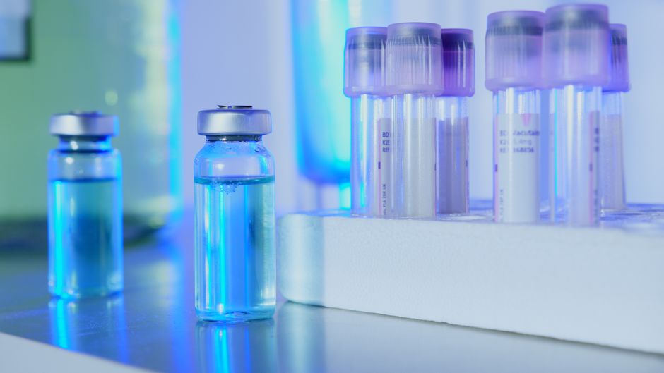 Flacons et tubes à essai contenant un liquide bleu en laboratoire sous lumière fluorescente