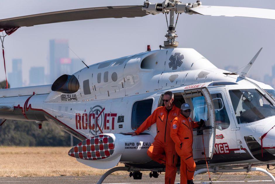 Une équipe médicale attend près d'un hélicoptère d'urgence en plein jour