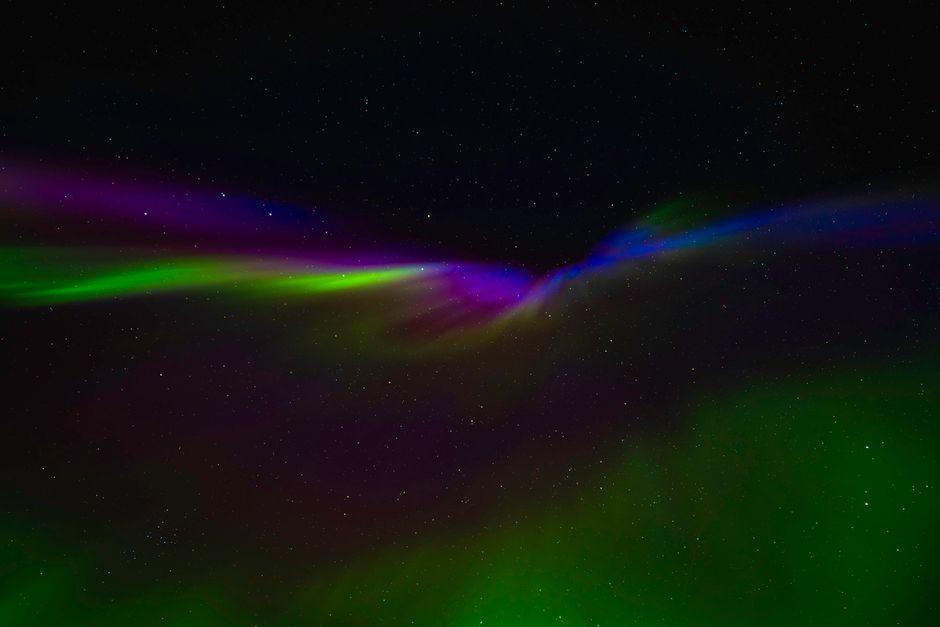 Aurores boréales vertes et violettes illuminant le ciel nocturne étoilé