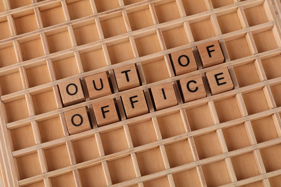 Lettres en bois formant le message « Absent du bureau » sur grille