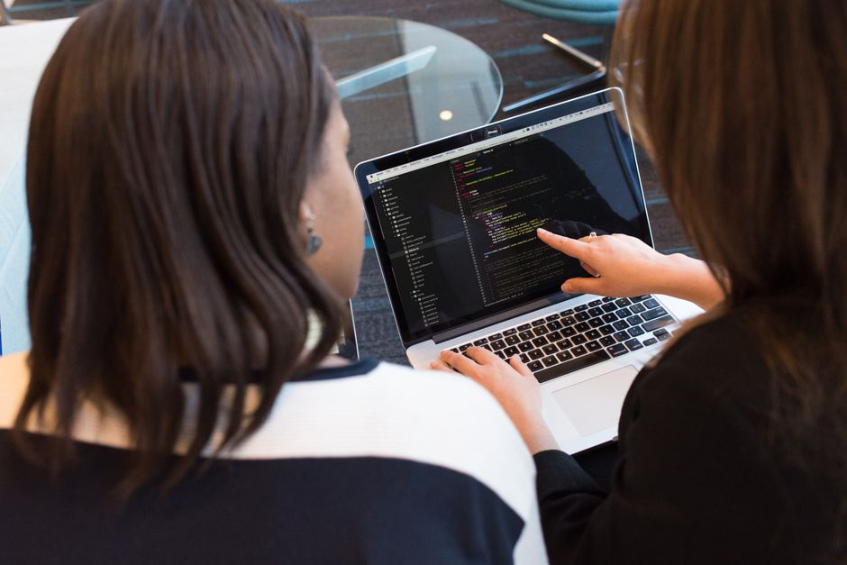 Deux développeuses collaborant sur du code informatique à l'écran