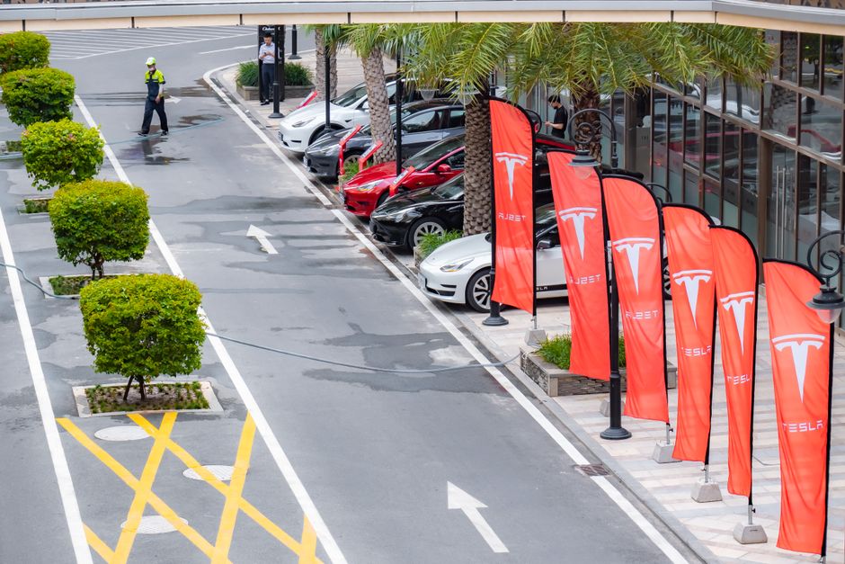Vue aérienne de voitures Tesla garées le long d'une rue avec drapeaux de marque