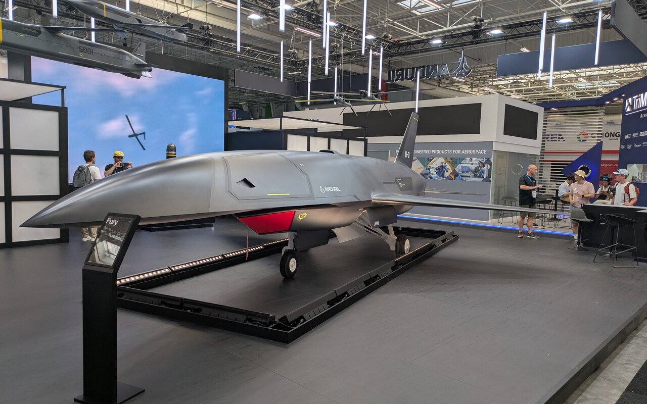 Un drone à réaction gris au fuselage effilé, posé sur un socle dans un hall de salon
