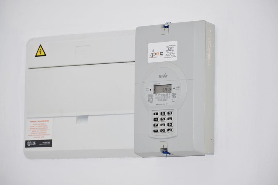 Compteur électrique et tableau de fusibles fixés à un mur blanc.