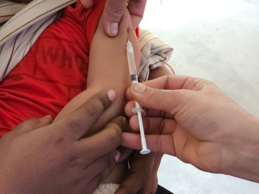 Un enfant reçoit une injection de vaccin par un professionnel de santé.