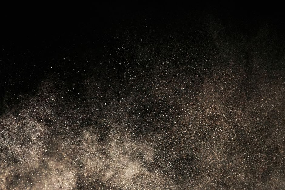 Particules de poussière flottant dans l'obscurité, créant une texture dense.